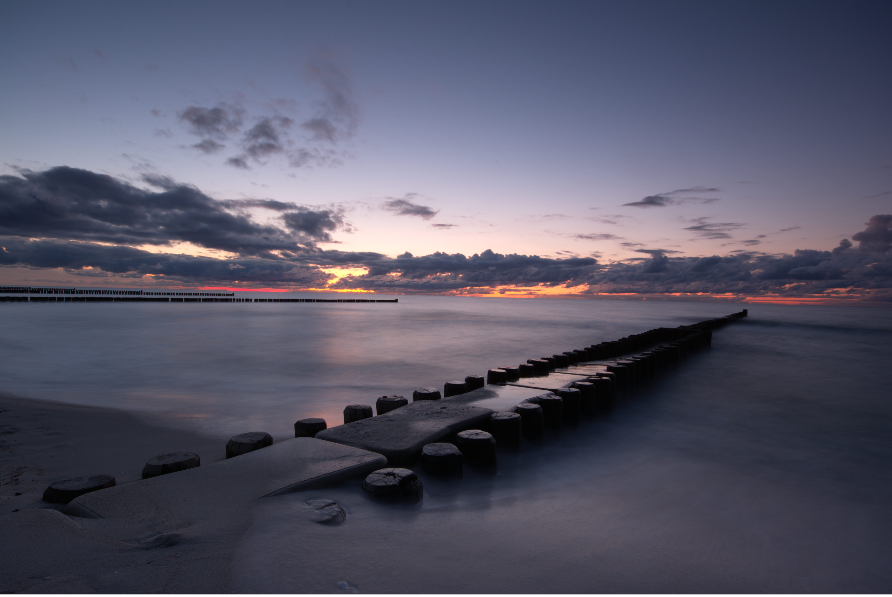 Steg, der ins Meer führt, mit Wolken im Hintergrund